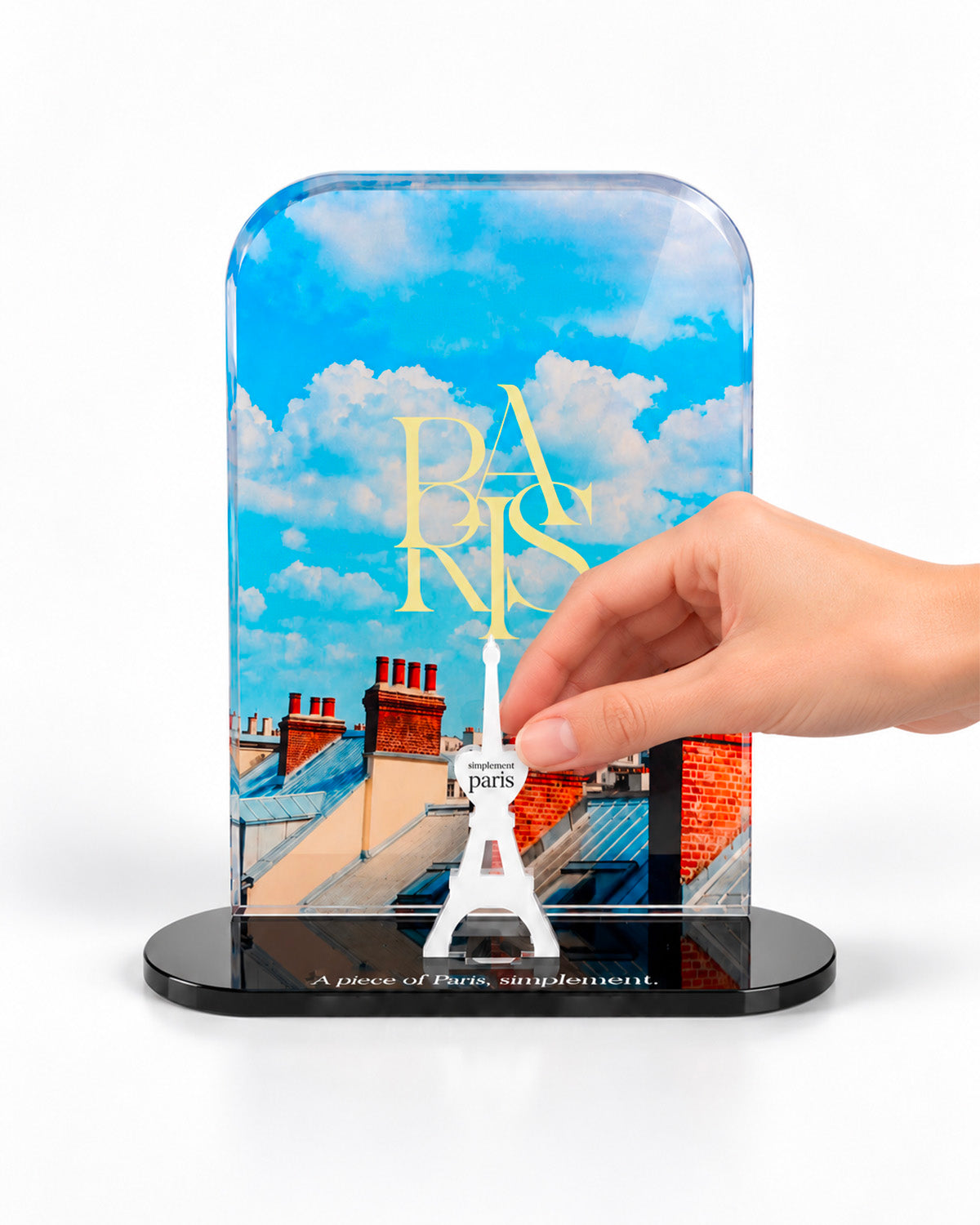 A hand placing the white signature Eiffel Tower into the glossy black base