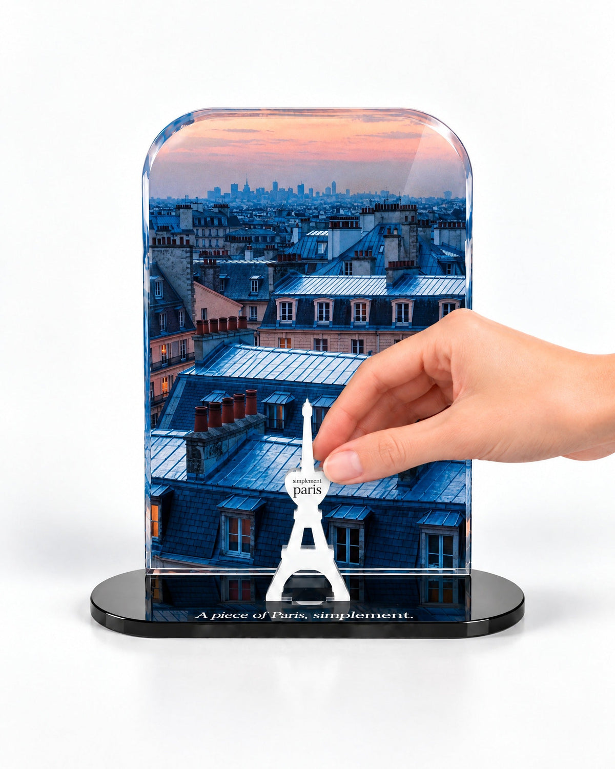 A hand placing the white signature Eiffel Tower in front of the Blue Hour Rooftops acrylic panel