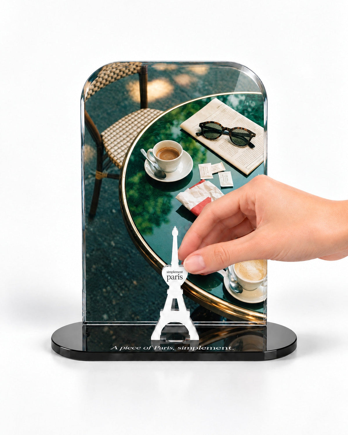 A hand placing the white signature Eiffel Tower in front of the Café Morning acrylic panel