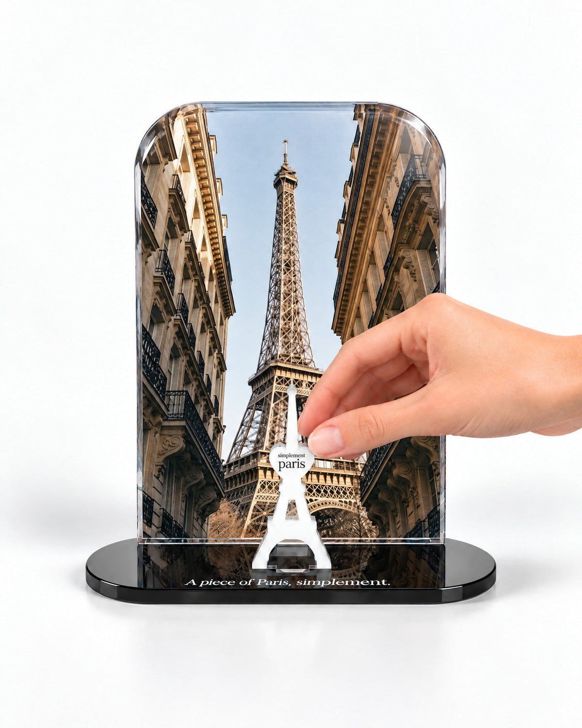 A hand placing the white signature Eiffel Tower in front of the Eiffel View acrylic panel