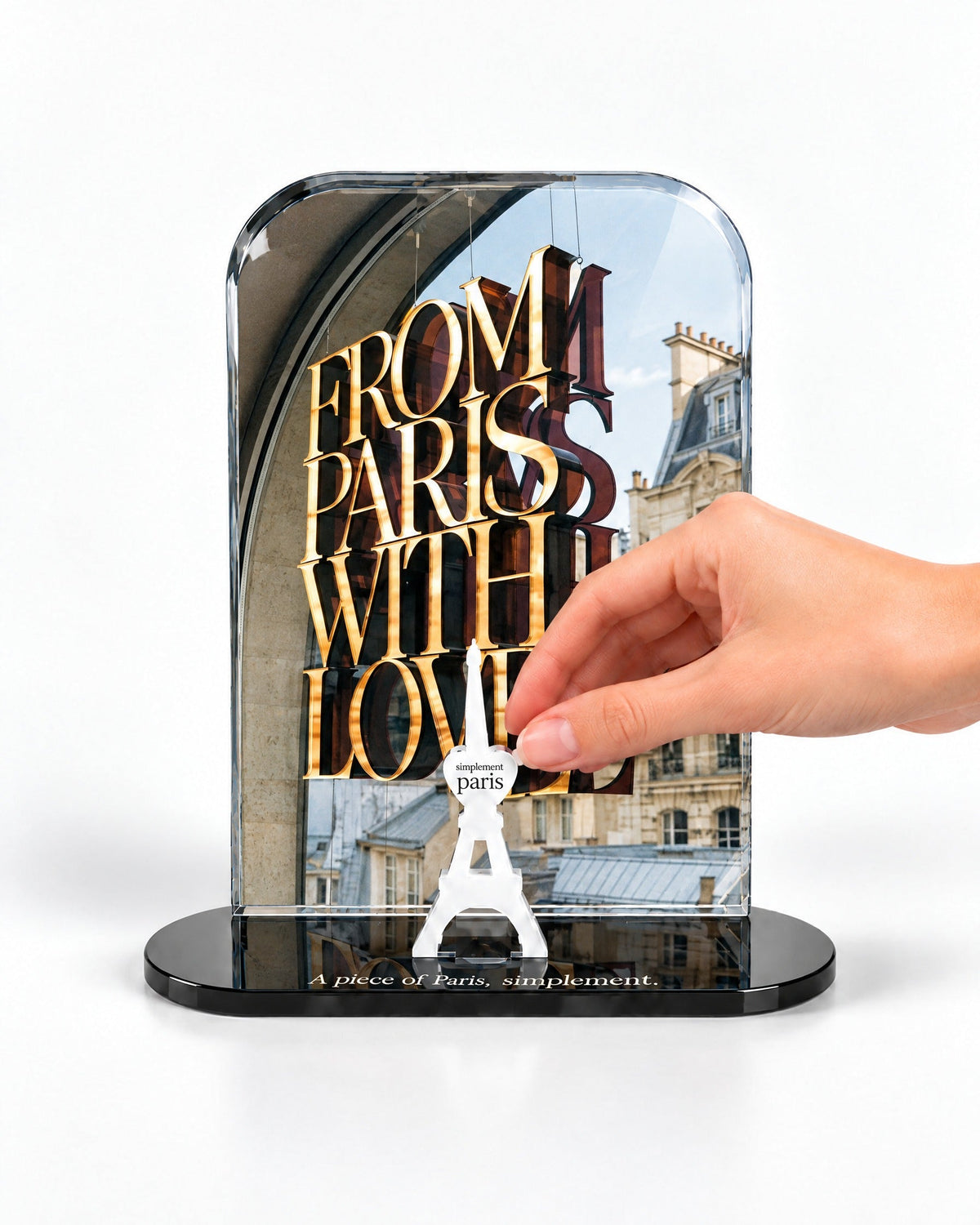A hand placing the white signature Eiffel Tower in front of the From Paris with Love acrylic panel