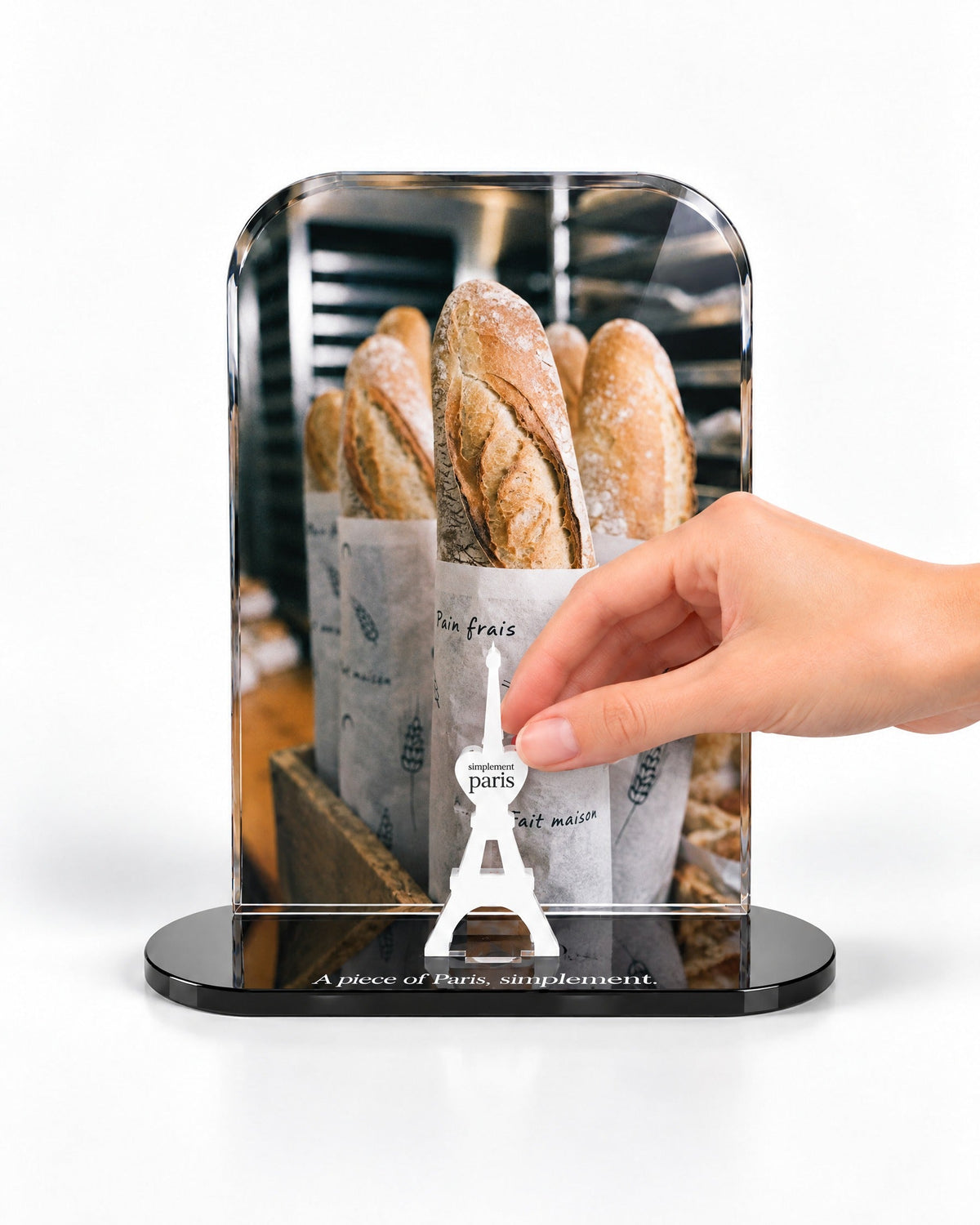 A hand placing the white signature Eiffel Tower in front of the La Baguette acrylic panel