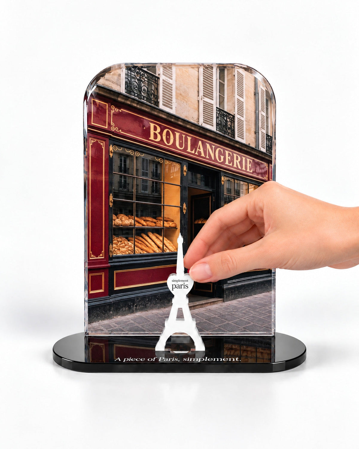 A hand placing the white signature Eiffel Tower in front of the La Boulangerie acrylic panel