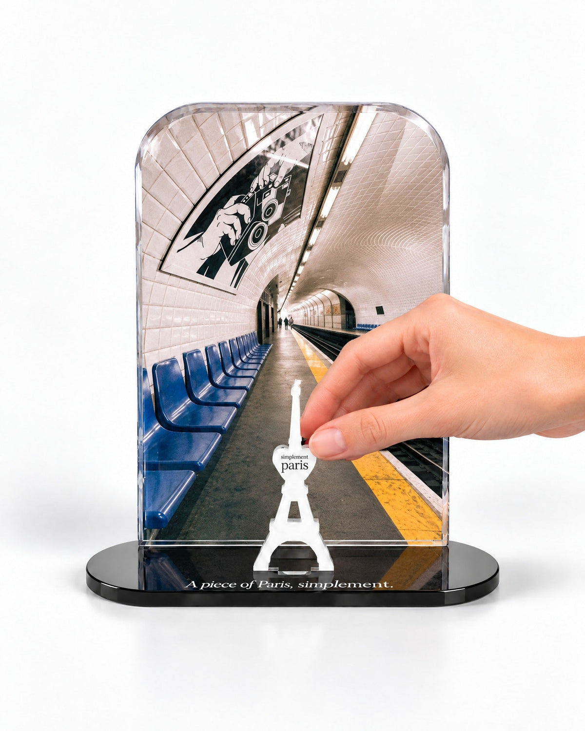 A hand placing the white signature Eiffel Tower in front of the Le Métro acrylic panel