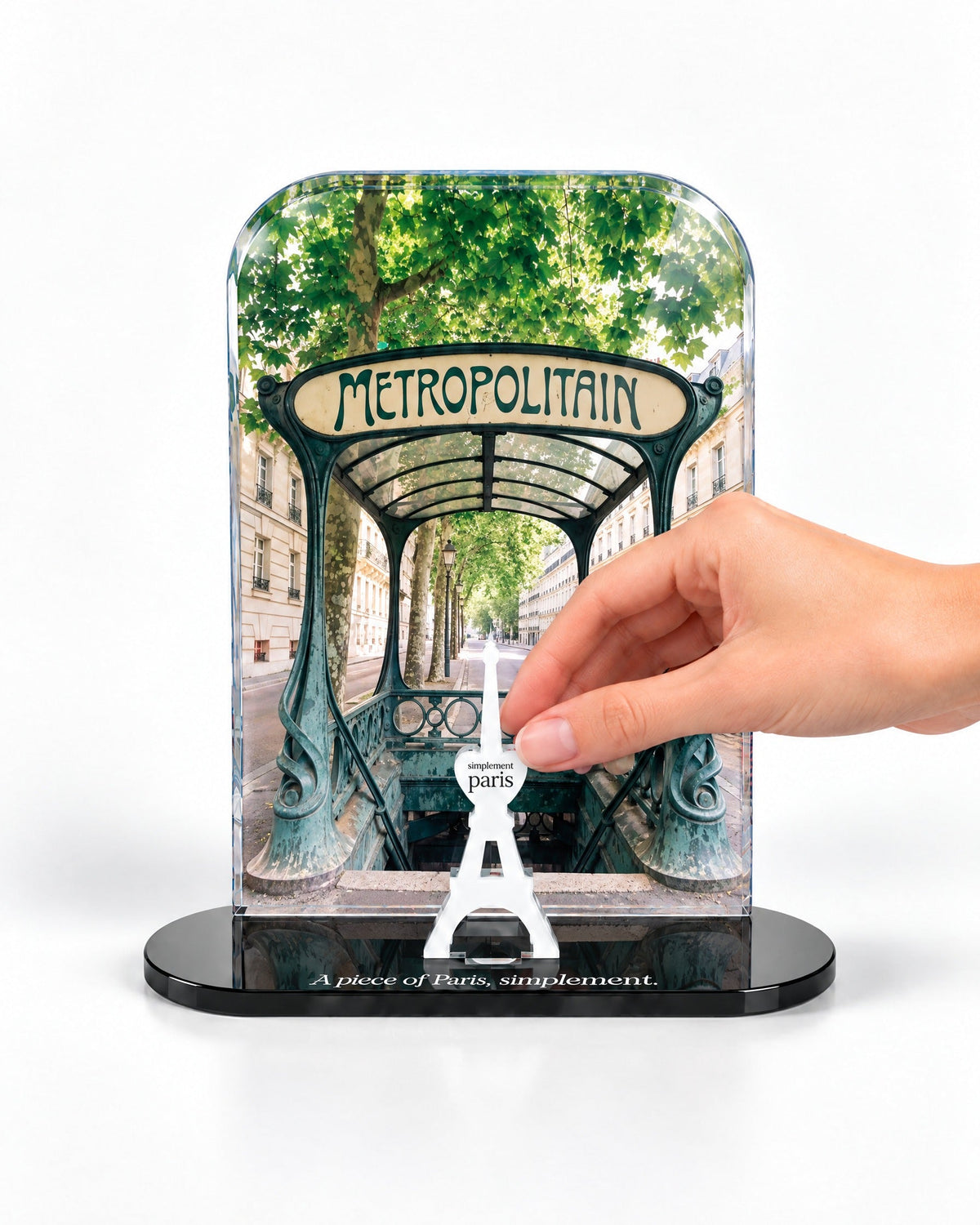 A hand placing the white signature Eiffel Tower in front of the Métropolitain acrylic panel