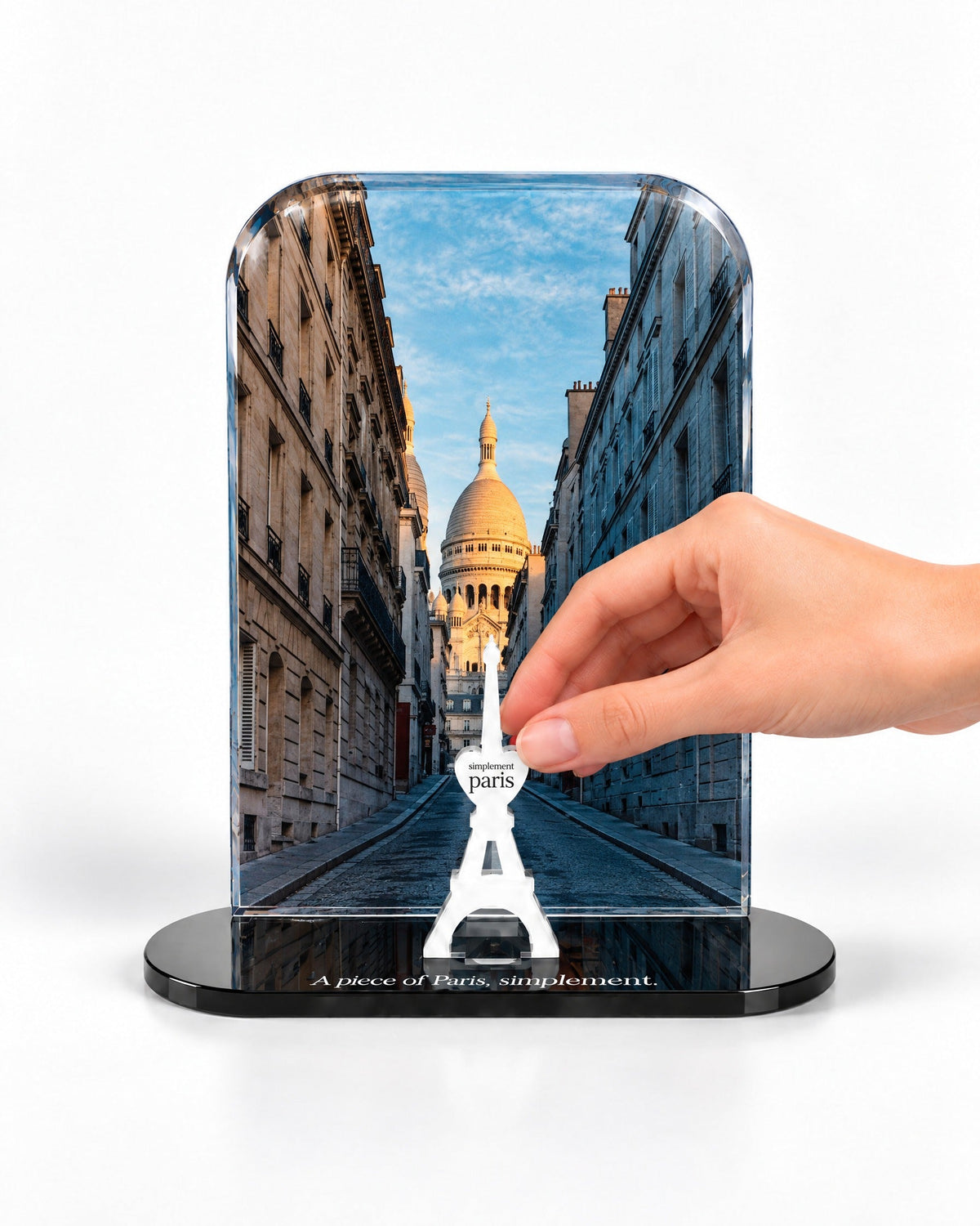 A hand placing the white signature Eiffel Tower in front of the Montmartre acrylic panel