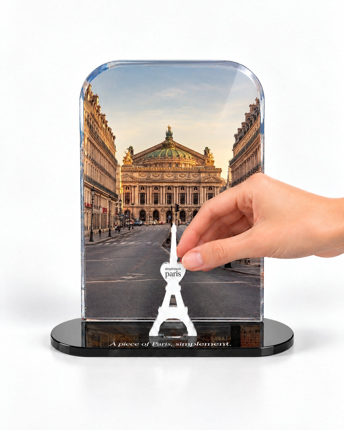 A hand placing the white signature Eiffel Tower in front of the Opéra Garnier acrylic panel