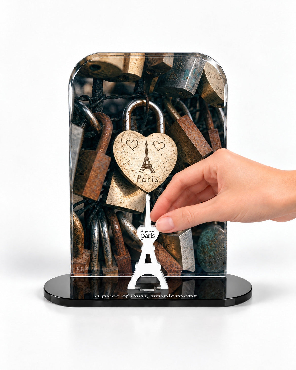 A hand placing the white signature Eiffel Tower in front of the Paris Love Lock acrylic panel