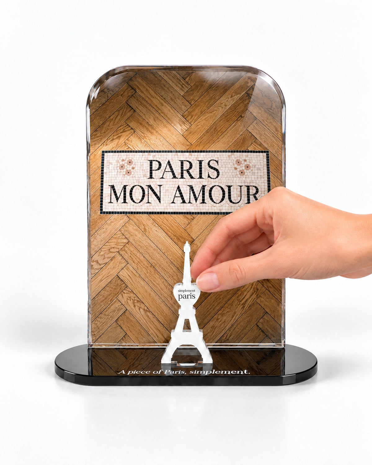A hand placing the white signature Eiffel Tower in front of the Paris Mon Amour acrylic panel