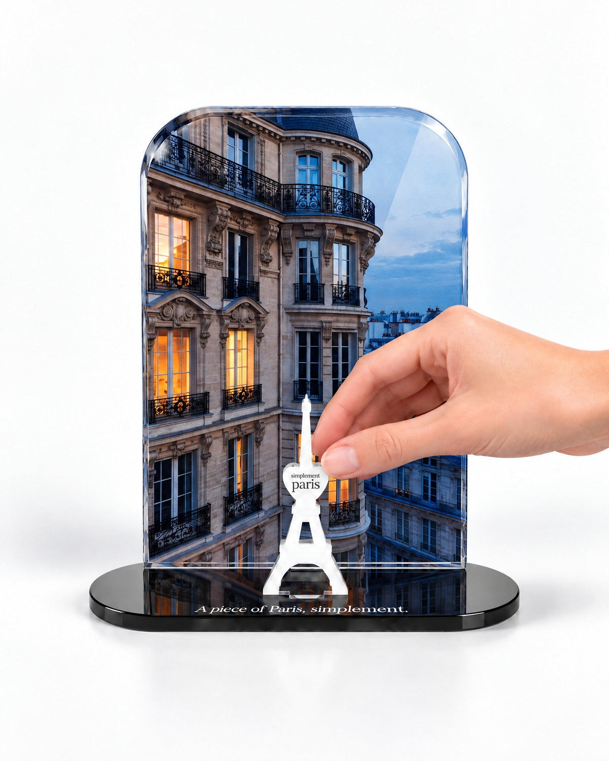 A hand placing the white signature Eiffel Tower in front of the Parisian Evening acrylic panel